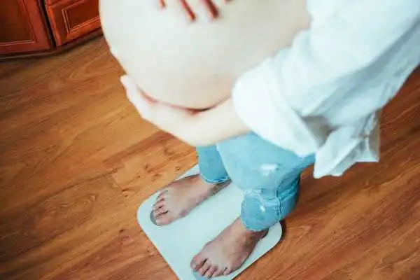 Image of woman weighing herself and experiencing weight gain through pregnancy Bibury